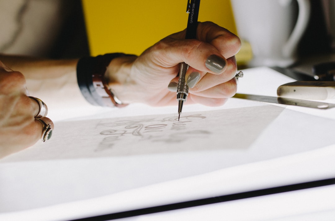 Ladies hand holding a pen while drawing on paper.